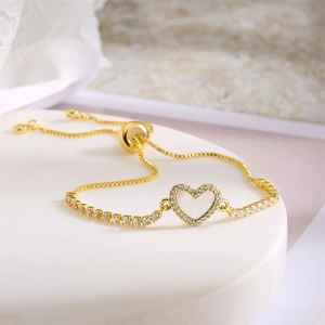 Detail of adjustable gold heart bracelet with clear zircon on a marble display stand
