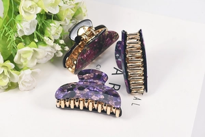 Close-up of three purple floral acrylic hair claws with gold-tone alloy spring detail