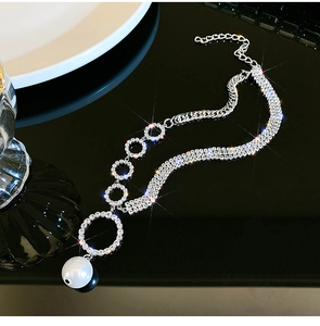 Detailed view of silver layered rhinestone necklace with large pearl pendant and round links