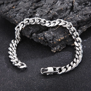 Polished silver stainless steel Cuban link bracelet with lobster clasp on dark stone background