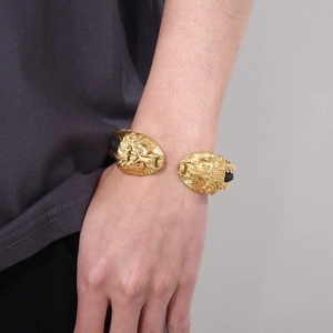 Detailed close-up of a men's wire bracelet featuring two golden lion head charms