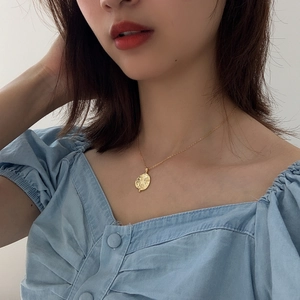 Close-up of a vintage-style gold 925 silver sun pendant necklace worn by a female model
