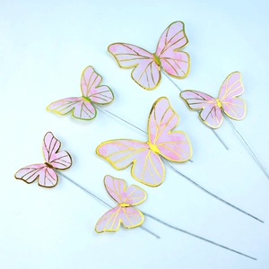 Set of 6 pink and gold foil butterfly cake toppers with wires on a blue background