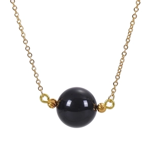Macro shot of 16mm polished black crystal pendant on a delicate gold chain necklace