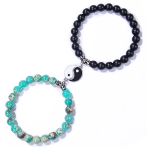 Detail of Yin Yang charms on matte black agate and turquoise stone beaded bracelets