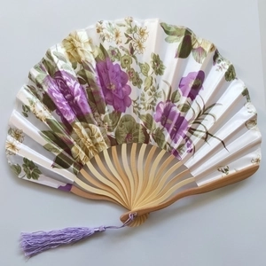 Detail of bamboo fan ribs with floral silk fabric and a purple silk tassel pendant