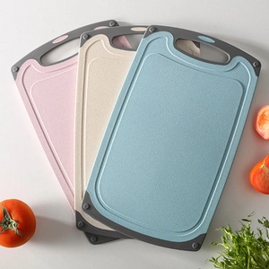 Three wheat straw cutting boards in pink, beige, and blue with non-slip rubber handles