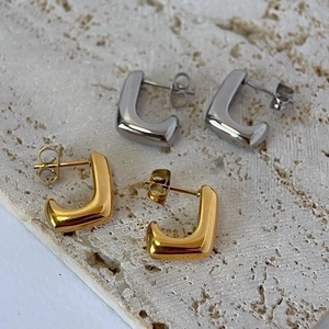 Minimalist 14k gold and silver geometric L-shaped stud earrings set on a stone surface