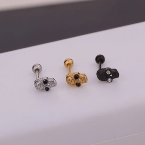Detalle macro de pendientes de calavera en plata, oro y negro con cierre de barra roscada