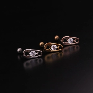Three safety pin stud earrings in silver gold and rose gold with zircon on dark surface