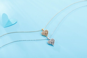 Détail des pendentifs en forme de cœur avec motifs tourbillons évidés en or et argent