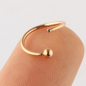 Rose gold titanium nose ring with small ball end shown on a fingertip for size scale