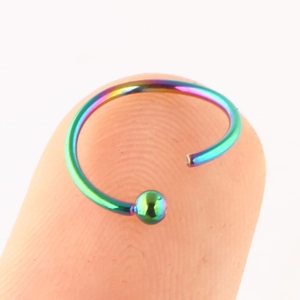 Rainbow titanium steel C-shaped nose ring with ball end shown on a fingertip