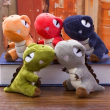 Group of colorful plush dinosaur toys in orange red blue green and grey on a wooden desk