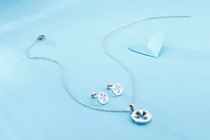 Detailed view of silver stainless steel angel necklace and earrings set on blue background
