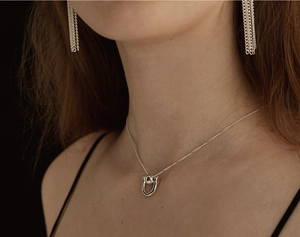 Close-up of a 925 sterling silver horseshoe pendant necklace on a model with black background