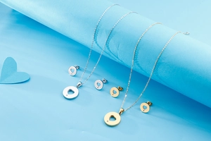 Detail of round hollow heart pendant necklaces and earrings set in gold and silver