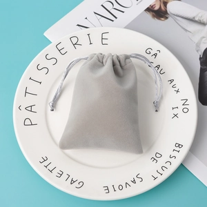 Elegant grey velvet drawstring pouch for jewelry gift storage on decorative plate