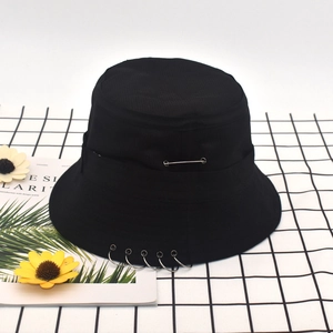 Detailed shot of black canvas bucket hat featuring silver metal rings and pin decorations