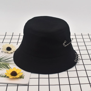 Detail of a black cotton bucket hat with silver rings and a metal safety pin accent
