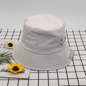 Detail of white canvas bucket hat with silver rings and safety pin accessory