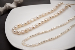 Dettaglio di due collane di perle d'acqua dolce barocche con texture naturale su un vassoio