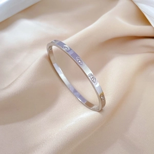 Detailed close-up of a silver titanium steel evil eye bangle on a silk background