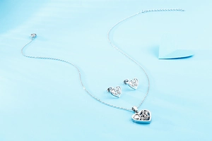 Detailed view of silver heart jewelry set with 'I Love You' engraving on blue background