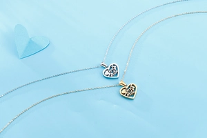 Close-up of gold and silver heart necklaces featuring engraved mãe text and tree design