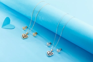 Detailed view of hollow heart pendants with tree of life and 'mãe' engraving set