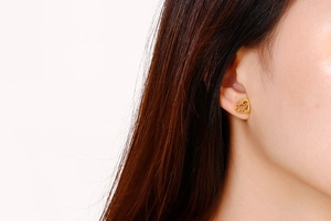 Gros plan de boucles d'oreilles cœur doré ajouré sur mannequin pour cadeau bijoux