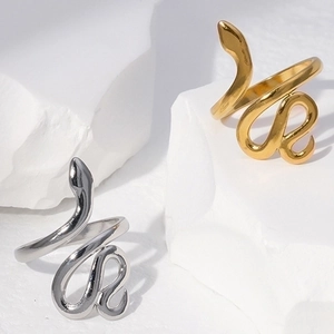 Adjustable snake-shaped stainless steel rings in gold and silver on white stone base