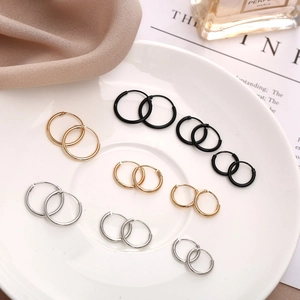 Detail of round hoop earrings set in gold silver and black finishes on white plate