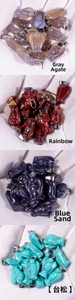 Detail of angel pendants in grey agate, rainbow stone, blue goldstone and turquoise