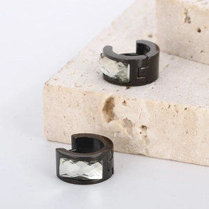 Macro detail of black stainless steel huggie earrings with faceted clear crystals