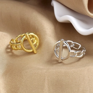 Anillos minimalistas de hebilla OT en oro y plata sobre tela de seda color champán