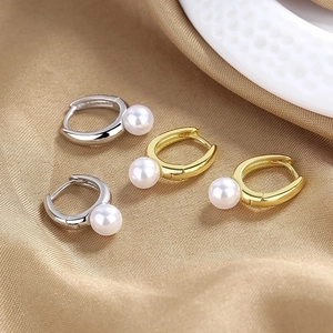 Elegant pearl hoop earrings in gold and silver finish on luxury champagne satin background