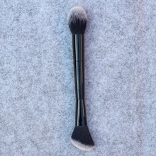 Close-up of a dual-ended makeup brush with black handle and soft synthetic bristles