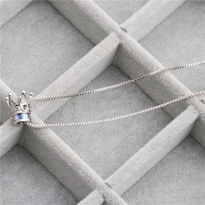 Crown pendant necklace with colorful gemstones and micro-pave zircons on a gray tray
