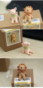 Cute resin animal figurines of a pink pig and brown lion in a minimalist gift box packaging