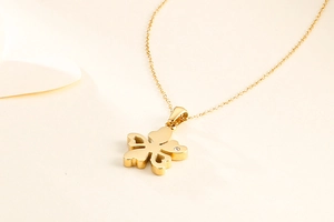 Détail d'un collier trèfle doré avec cœur ajouré et petits diamants incrustés