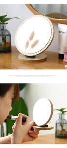 Macro shot of 360-degree rotating wooden makeup mirror on a vanity with natural lighting