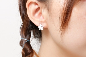 Gros plan d'une boucle d'oreille fleur argentée portée par un mannequin avec style
