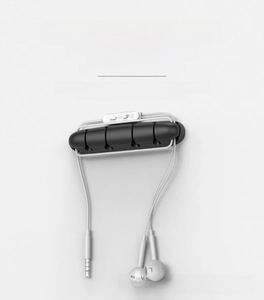 Close-up of 5-slot black silicone cable organizer for desk with white earphones