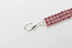 Macro detail of three-row pink rhinestone pet collar buckle with silver lobster clasp