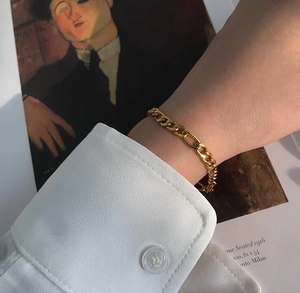 Pulsera Figaro minimalista bañada en oro de 18K para mujer con camisa blanca