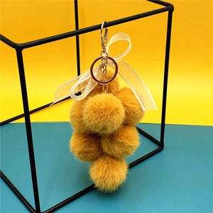 Cute plush grape keychain with yellow fur balls, lace bow, and golden metal clasp