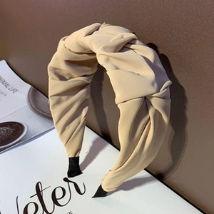 Detail of a creamy beige twisted headband showing pleated fabric texture and knot