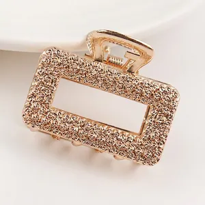Detail of gold rectangular hair claw with intricate rose flower relief textures