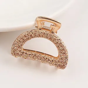 Detail view of golden half-moon hair claw clip with floral rose relief pattern